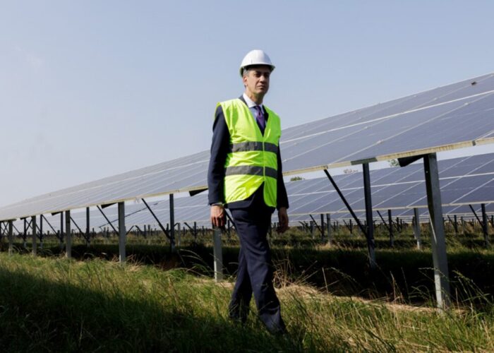Ed Miliband walks in front of solar panels.